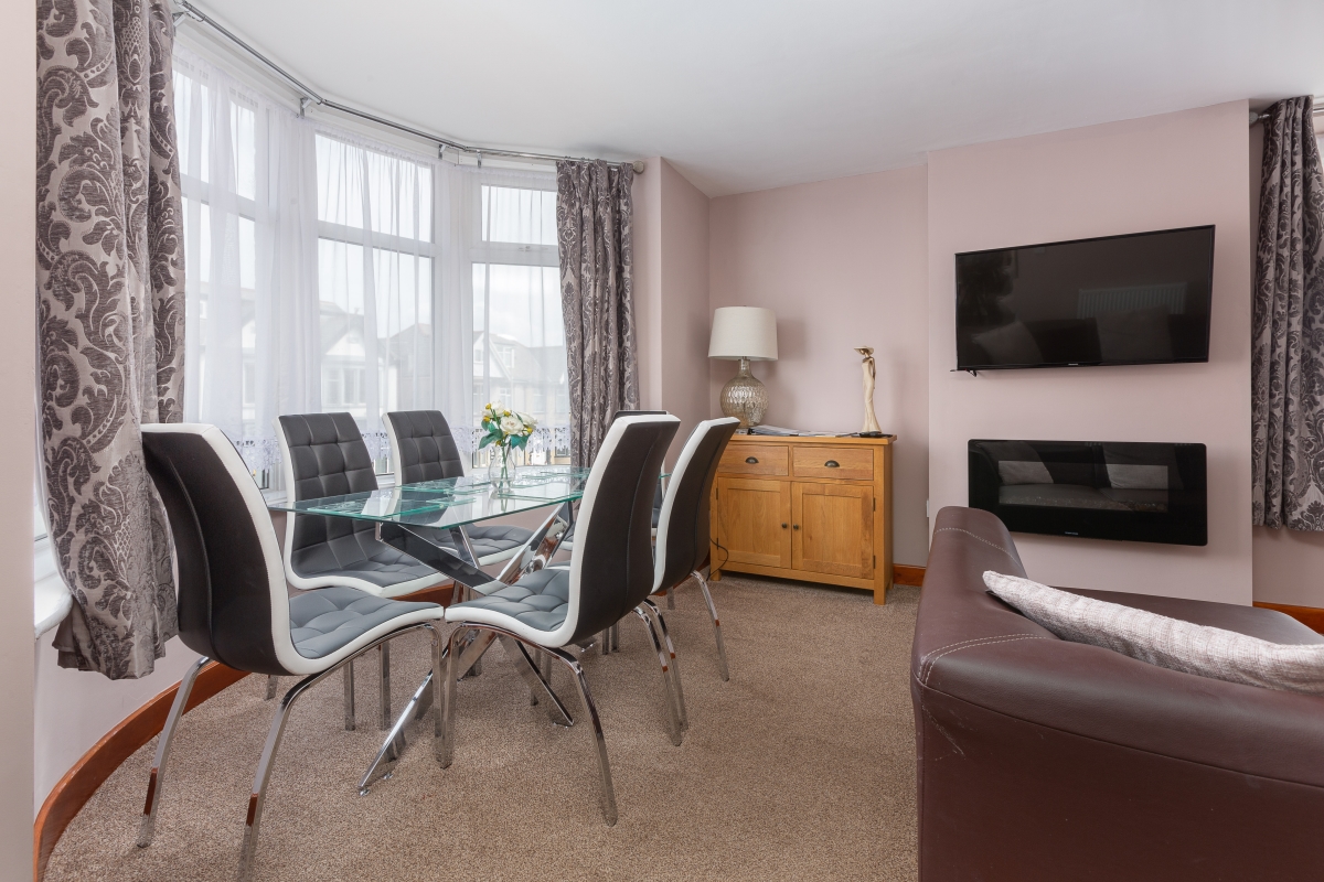 Self catering holiday apartments Blackpool. Beachcliffe apartments  7 lounge. Large double sofa bed, wall mounted TV, coffee table, Dining area with Table and chairs set in a bay window with sea views.