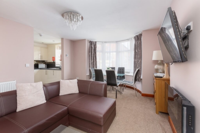 Self catering holiday apartments Blackpool. Beachcliffe apartments  7 lounge. Large double sofa bed, wall mounted TV, coffee table, Dining area with Table and chairs set in a bay window with sea views.